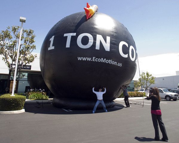 A man gets his photo taken with a 26-foot balloon in the parking lot at EcoMotion in Irvine on Wednesday. The balloon represents one ton of CO2 gas. The company was doing a test run for inflating the balloon and will use it as an educational tool in their "Save a Ton" campaign.      ///ADDITIONAL INFO:                  01.timbbomb.0426.pb      Shot:  04/24/12         Paul Bersebach, The Orange County Register